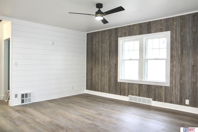 unfurnished room featuring ceiling fan, dark wood-type flooring, and wood walls