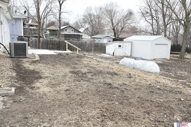 view of yard featuring central AC unit, a garage, and a storage shed