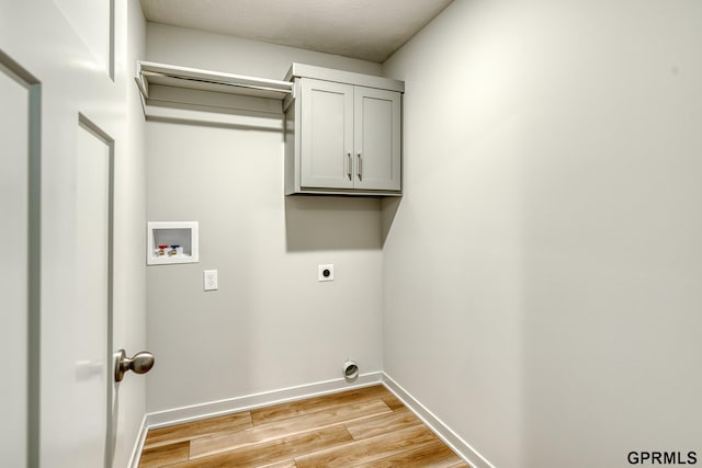 laundry room with electric dryer hookup, hookup for a washing machine, cabinets, and light wood-type flooring