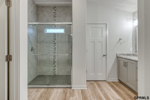 bathroom featuring vanity, hardwood / wood-style floors, a textured ceiling, and an enclosed shower