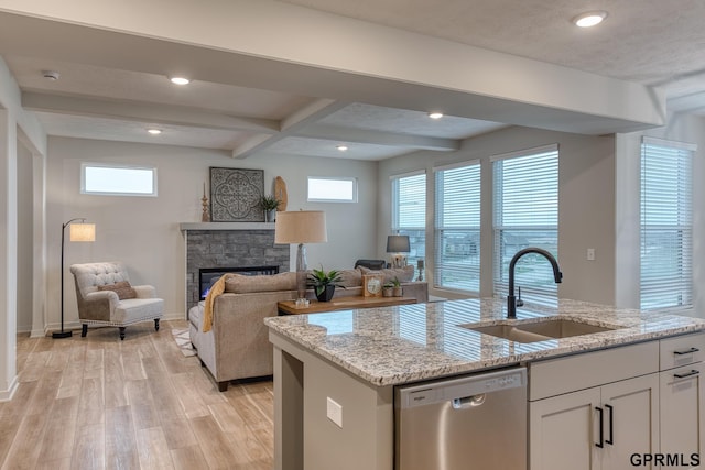 kitchen with white cabinetry, dishwasher, sink, and light stone countertops