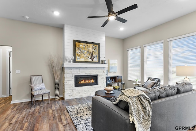 living room with ceiling fan, a fireplace, and dark wood-type flooring