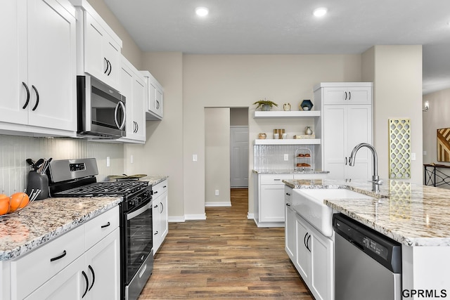 kitchen with light stone countertops, dark hardwood / wood-style flooring, stainless steel appliances, sink, and white cabinets