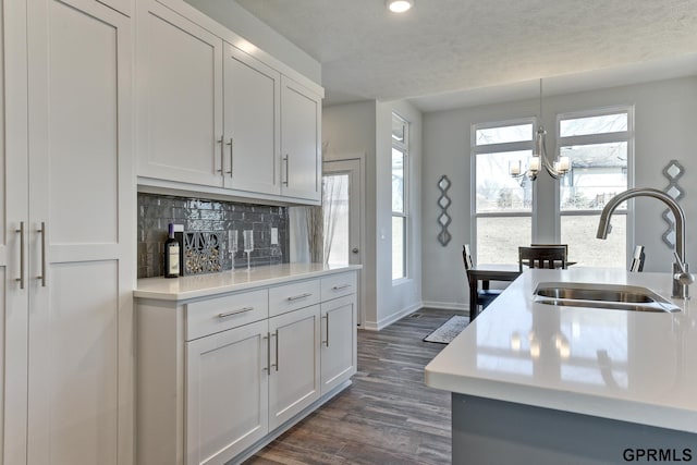 kitchen with sink, hanging light fixtures, tasteful backsplash, a notable chandelier, and white cabinetry