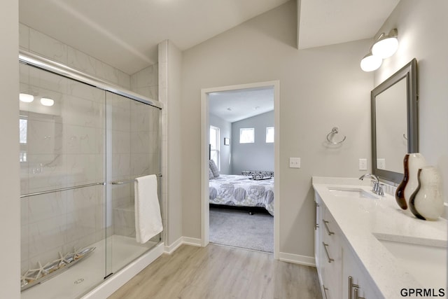 bathroom featuring wood-type flooring, vanity, walk in shower, and lofted ceiling