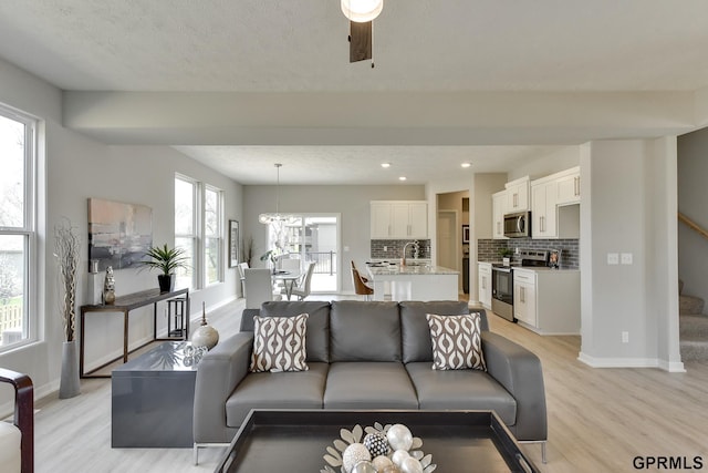 living room with ceiling fan, sink, a healthy amount of sunlight, and light wood-type flooring