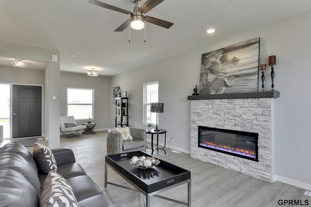 living room featuring ceiling fan, light wood-type flooring, and a fireplace