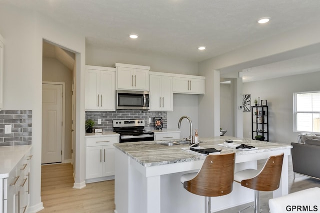 kitchen featuring white cabinetry, sink, appliances with stainless steel finishes, and an island with sink