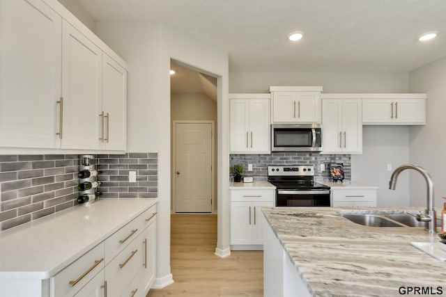 kitchen featuring white cabinets, sink, decorative backsplash, appliances with stainless steel finishes, and light stone counters