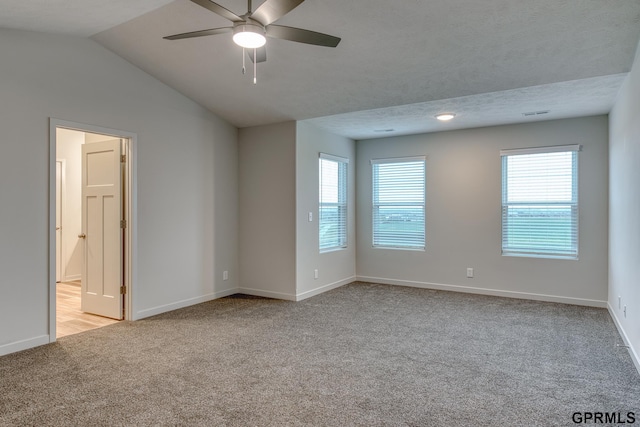 carpeted spare room with a textured ceiling, ceiling fan, and vaulted ceiling