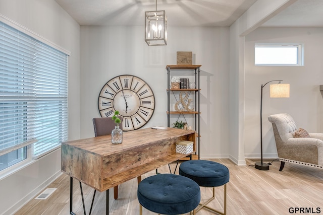 office with a wealth of natural light, an inviting chandelier, and light wood-type flooring