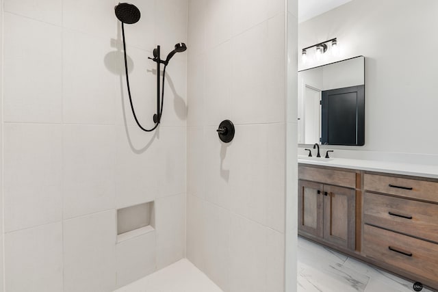 bathroom with tiled shower and vanity