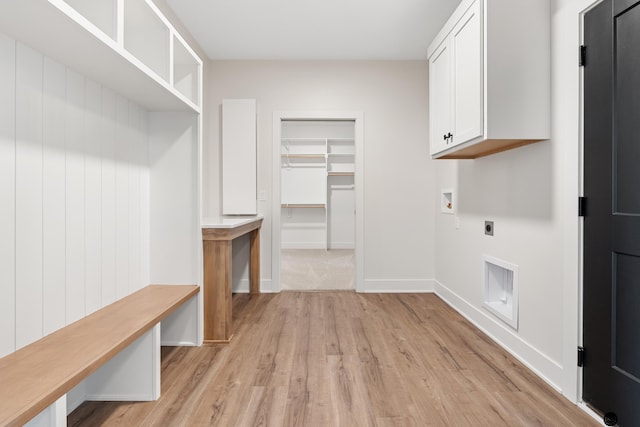 washroom featuring hookup for an electric dryer, washer hookup, light hardwood / wood-style floors, and cabinets