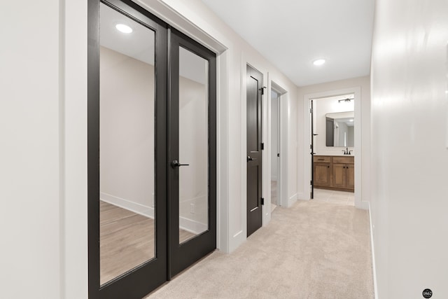 hallway featuring light colored carpet and sink