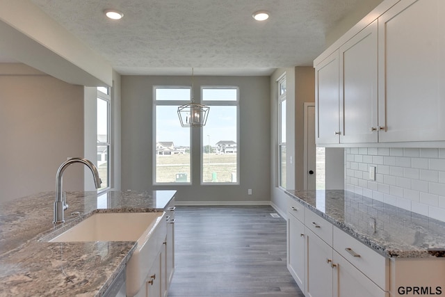 kitchen with white cabinets, decorative light fixtures, light stone countertops, and tasteful backsplash