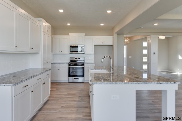 kitchen featuring white cabinetry, a kitchen island with sink, sink, and appliances with stainless steel finishes