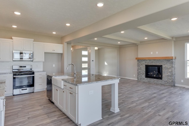 kitchen featuring sink, white cabinetry, an island with sink, and appliances with stainless steel finishes