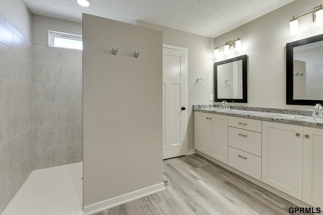 bathroom featuring hardwood / wood-style floors, vanity, a shower, and a textured ceiling