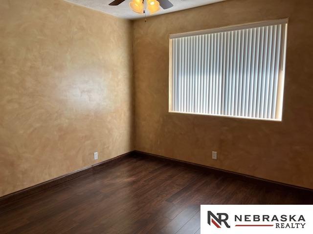 unfurnished room featuring ceiling fan and dark wood-type flooring