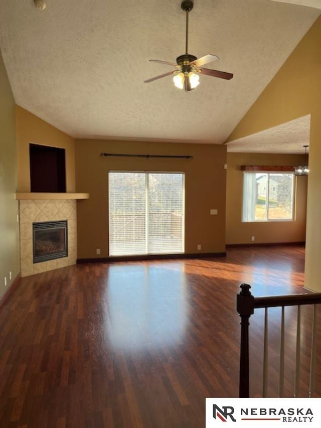 unfurnished living room featuring a textured ceiling, ceiling fan with notable chandelier, lofted ceiling, and a fireplace