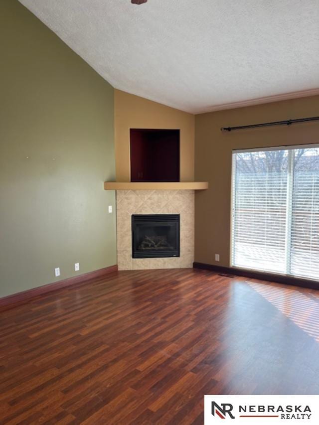 unfurnished living room featuring hardwood / wood-style floors, lofted ceiling, a premium fireplace, and a textured ceiling