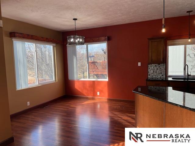 unfurnished dining area with a textured ceiling, dark hardwood / wood-style floors, an inviting chandelier, and sink