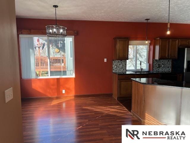 kitchen featuring sink, dark wood-type flooring, a textured ceiling, decorative light fixtures, and decorative backsplash