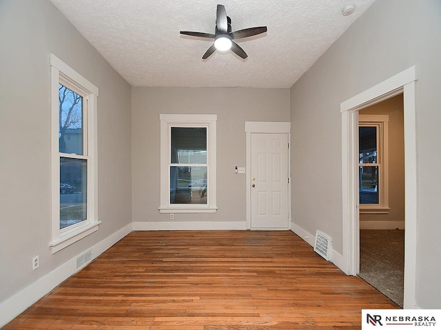 empty room featuring light wood-type flooring, a textured ceiling, and ceiling fan