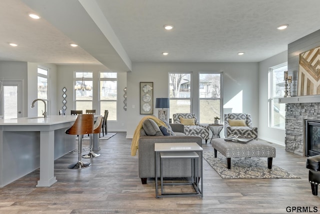 living room featuring a fireplace, wood-type flooring, an inviting chandelier, and sink