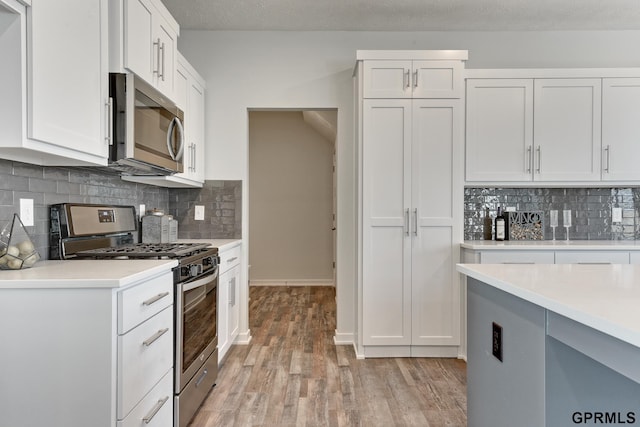 kitchen featuring backsplash, white cabinetry, stainless steel appliances, and a textured ceiling