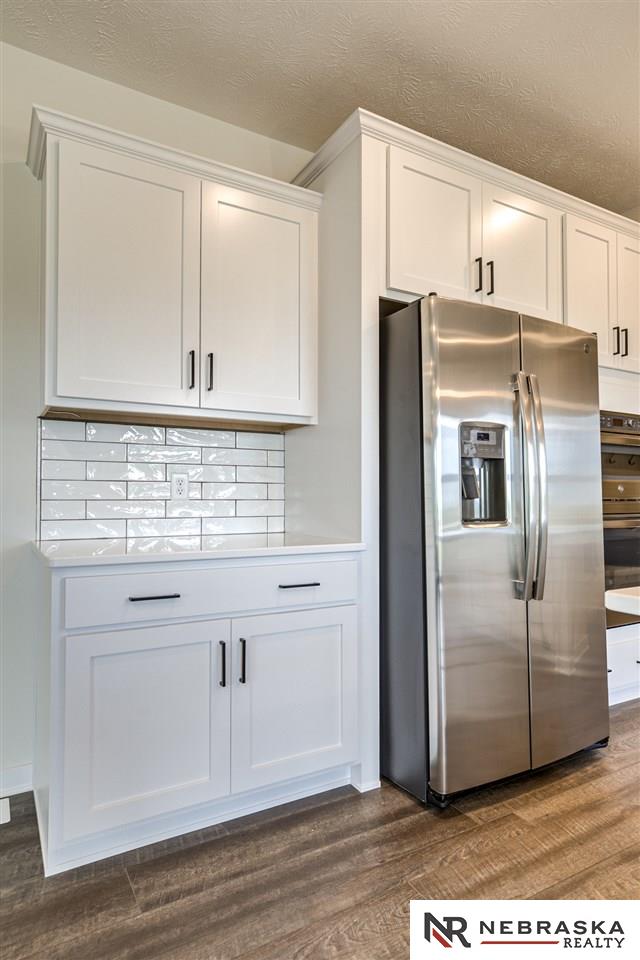 kitchen with backsplash, white cabinets, dark hardwood / wood-style floors, and stainless steel refrigerator with ice dispenser