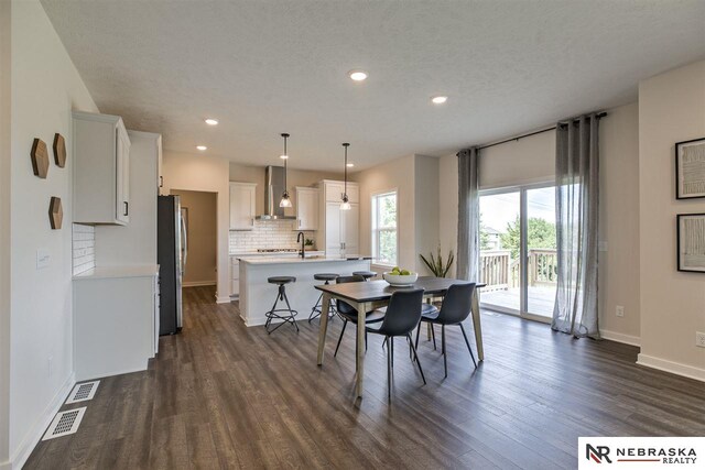 dining space featuring a textured ceiling, sink, and dark wood-type flooring