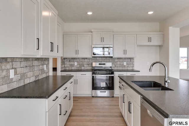 kitchen with white cabinetry, sink, tasteful backsplash, light hardwood / wood-style flooring, and appliances with stainless steel finishes