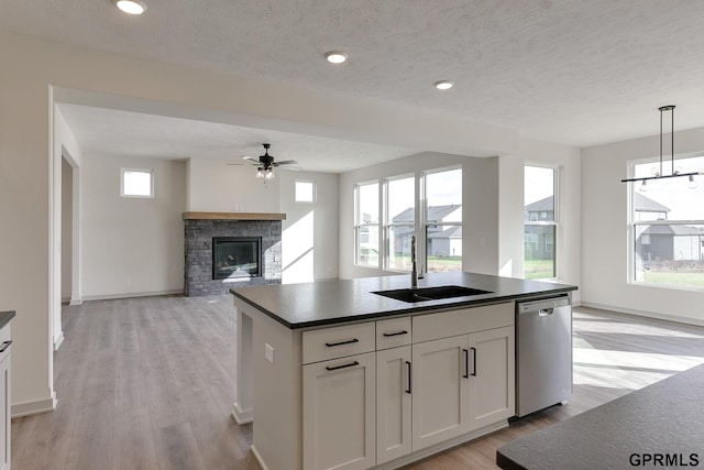 kitchen with a fireplace, sink, dishwasher, white cabinetry, and hanging light fixtures