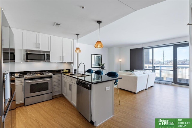 kitchen with white cabinetry, sink, kitchen peninsula, light hardwood / wood-style floors, and appliances with stainless steel finishes