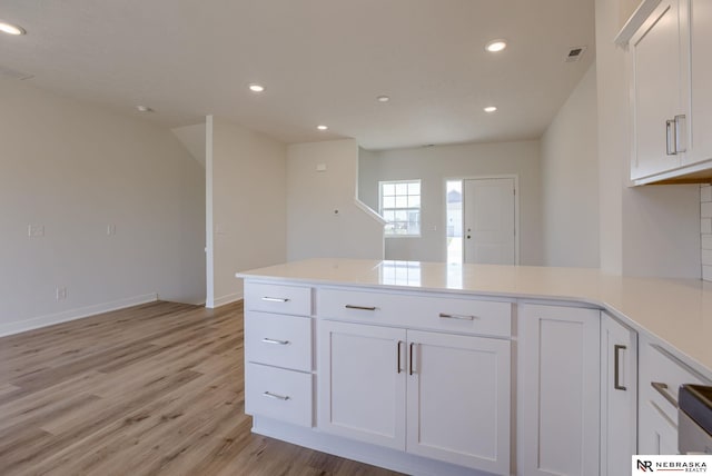 kitchen featuring white cabinets, light hardwood / wood-style floors, and kitchen peninsula