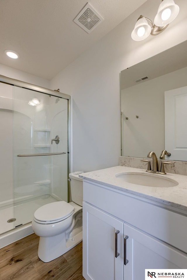 bathroom featuring vanity, hardwood / wood-style flooring, toilet, and a shower with shower door