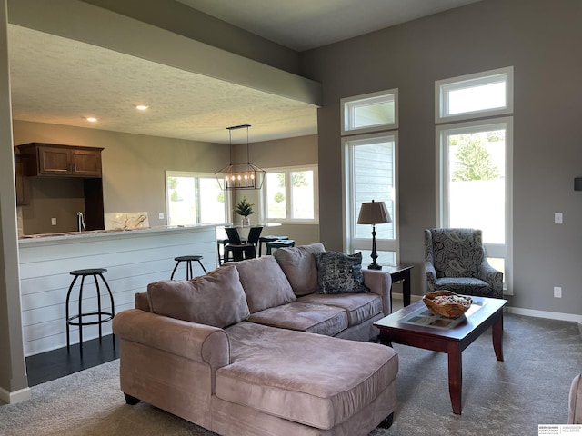 living room with a chandelier and dark colored carpet