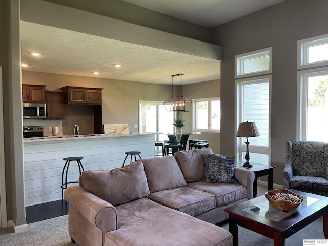 carpeted living room with a healthy amount of sunlight and a chandelier