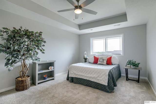 bedroom with ceiling fan, carpet floors, and a tray ceiling