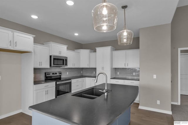 kitchen with decorative light fixtures, stainless steel appliances, a center island with sink, and sink