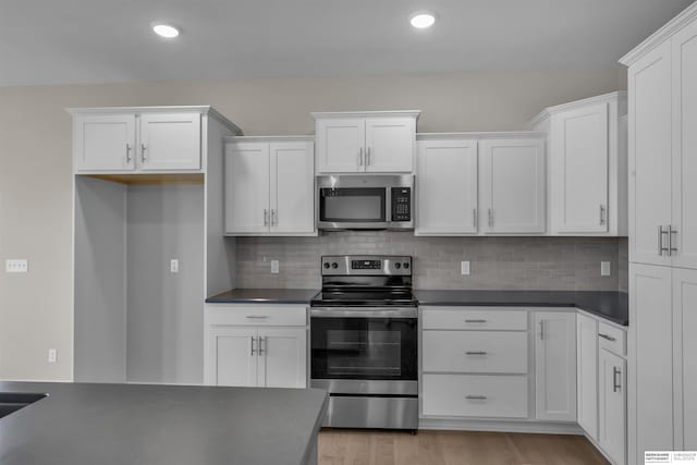 kitchen with tasteful backsplash, white cabinets, and stainless steel appliances