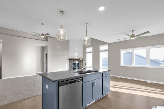 kitchen with plenty of natural light, a kitchen island with sink, sink, stainless steel dishwasher, and decorative light fixtures