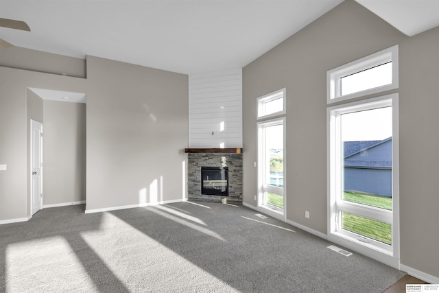 unfurnished living room with a fireplace, a towering ceiling, and carpet flooring