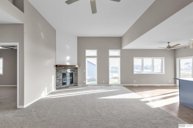 unfurnished living room with a wealth of natural light, ceiling fan, and a fireplace