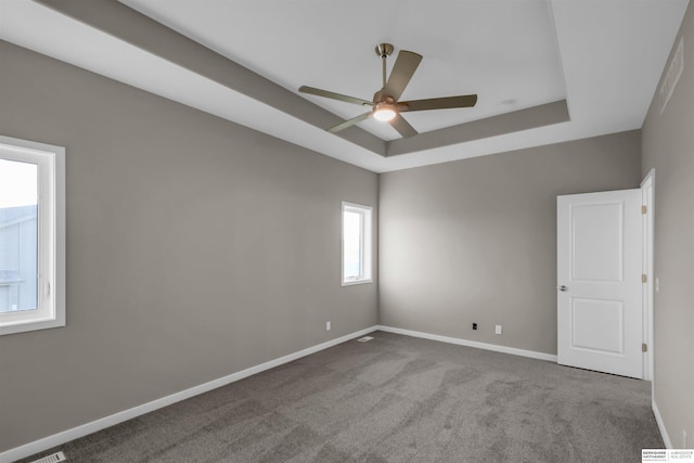 spare room featuring light colored carpet, ceiling fan, and a tray ceiling