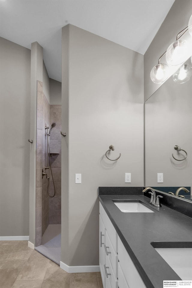 bathroom with tiled shower, vanity, and tile patterned floors