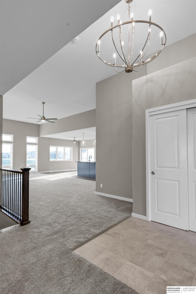 interior space featuring light carpet and ceiling fan with notable chandelier