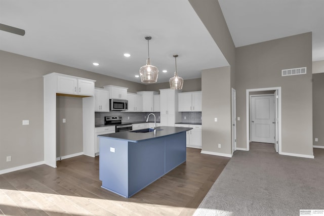 kitchen featuring pendant lighting, white cabinets, sink, an island with sink, and stainless steel appliances