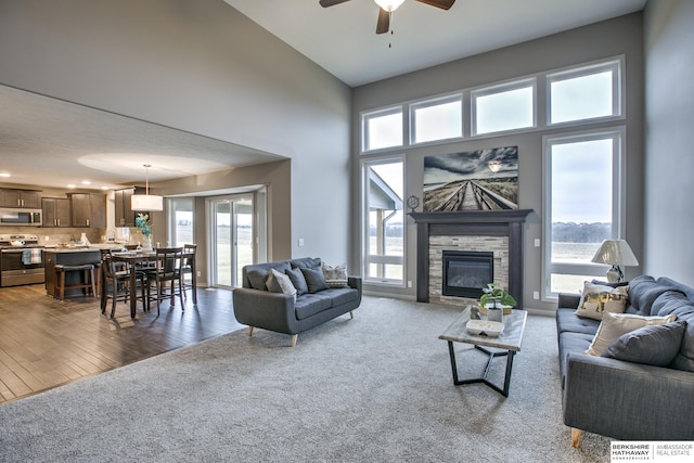 carpeted living room with a fireplace, a high ceiling, and ceiling fan